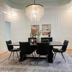 a dining room table with black chairs and a chandelier hanging from the ceiling