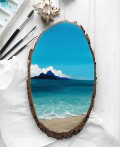 an oval mirror sitting on top of a table next to paintbrushes and other items