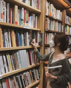 a woman wearing a face mask is looking at books in a library