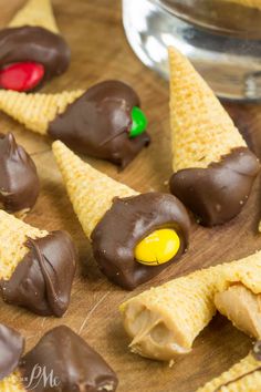 chocolate covered candy cones are arranged on a cutting board next to a bowl of candy