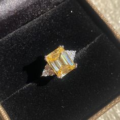 a yellow diamond ring sitting on top of a velvet case