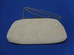 This eye-catching beaded purse with gold colored trim and double chain was made in Hong Kong in the 1950's. It's lined in a soft cream colored satin material and has an inside pocket. The chain can be tucked inside, turning it into a lovely clutch purse. All the beadwork is intact as far as I can tell and the purse is in very good, clean condition inside and out. It measures 9 1/2" by 5 1/2". Item# Misc-230 At The Thorny Thistle, we know there's still a place for these wonderful and well-loved v Cream Beaded Evening Bag, Formal Beaded Cream Evening Bag, Formal Cream Beaded Evening Bag, Colored Trim, Beaded Clutch, Beaded Purses, Double Chain, Satin Material, Clean Hands