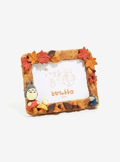 a small frame with an animal and autumn leaves on the edge, sitting in front of a white background