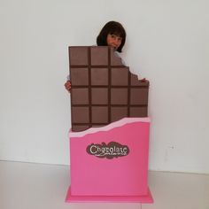 a woman standing behind a giant chocolate bar