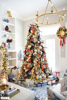 a christmas tree decorated with red, white and blue ornaments in a living room setting