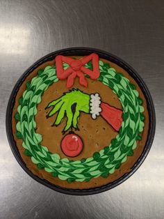 a cookie decorated with green and red icing on top of a metal surface in the shape of a wreath