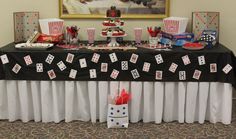 a black table topped with cards and cupcakes next to a painting on the wall