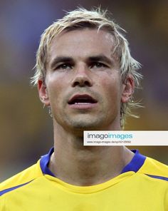 a man with blonde hair wearing a yellow and blue soccer uniform looking off to the side