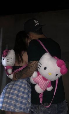 a man holding two hello kitty stuffed animals