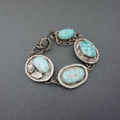 This lovely gemstone bracelet is one of a kind and a great statement piece!  Each charm link has been embellished in a very unique way to make a one of a kind bracelet. The lovely turquoise stones  are of the highest quality. I have used 2 Cloud Mine Turquoise stones with 2 Sleeping Beauty Stones. The turquoise contrasts beautifully with the oxidized sterling silver. I have added a variety of embellishments to the outside of the stones and then finished the bracelet with a handcrafted hook clasp. The bracelet is about 7" and is somewhat adjustable.  The bracelet will be sent in a linen bag, inside a gift box, ready for gift giving! *Take a closer look* 4 turquoise cabochons- Cloud Mine and Sleeping Beauty hook clasp Length-7" adjustable *Surface Features* Granulation Square wire oxidation Unique Turquoise Sterling Silver Bracelets, Handmade Turquoise Sterling Silver Bracelets, Unique Turquoise Metal Bracelet, Handmade Turquoise Bracelet Jewelry, Handmade Turquoise Bracelet, Sterling Silver Jewelry With Turquoise, Unique Turquoise Bracelet Jewelry, Turquoise Metal Bracelet Jewelry, Artisan Turquoise Gemstone Bracelet