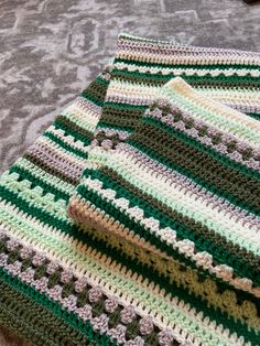 a green and white crocheted blanket sitting on top of a carpeted floor