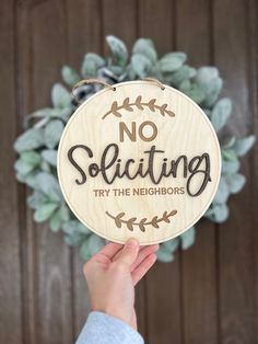 someone holding up a wooden sign that says no solicing try the neighbor