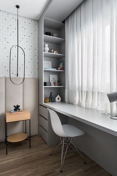 a room with a desk, chair and book shelf in the corner next to a window