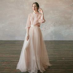 a woman in a white dress standing on a wooden floor with her hands behind her head