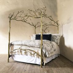 a gold metal bed frame with branches on the headboard and foot board, against a white wall