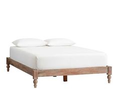 a bed with two white pillows on top of it and wooden frame around the headboard