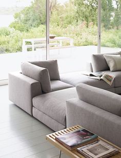 a living room filled with furniture next to a large glass window covered in lots of windows