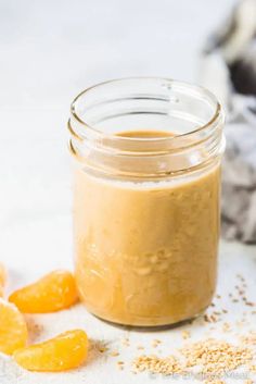 a jar filled with peanut butter and oranges on top of a white tablecloth