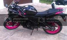 a black and pink motorcycle parked in front of a garage