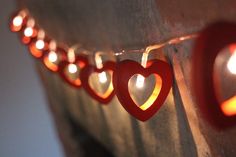 some lights are hanging on the wall with heart shaped ones attached to each one's sides