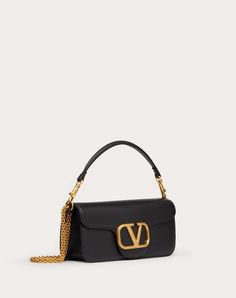 Valentino Garavani Locò shoulder bag in calfskin with metallic VLogo Signature detail. The bag can be worn on the shoulder/crossbody or carried by hand thanks to the detachable handle and the detachable sliding chain. - Antique-finish Brass hardware - Magnetic closure - Detachable leather handle - Shoulder strap with detachable sliding chain - Nappa lining. Interior: one flat pocket - Drop length: min 26 cm - max 50 cm - Dimensions: W27xH13xD6 cm - Weight: 0.5 kg - Made in Italy Valentino Bag Black, Valentino Bag, Ikea Kids, Handbag Collection, Girly Accessories, Valentino Bags, Leather Slides, Small Shoulder Bag, Stylish Bag