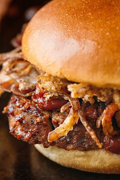 a pulled pork sandwich on a bun with barbecue sauce and onions, sitting on a table