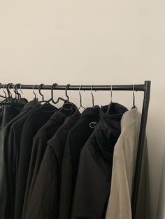 clothes hanging on a rail in front of a white wall and black coat hangers