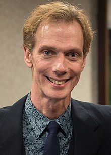 a man in a suit and tie smiling at the camera