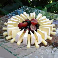 a cake with cheese, fruit and other toppings sitting on a glass platter