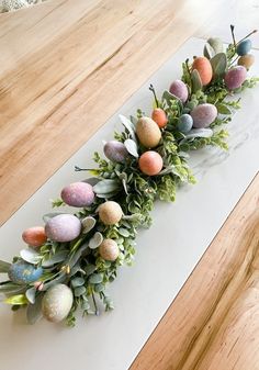 an arrangement of eggs and greenery on a white counter top with wood flooring