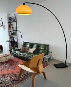 a living room with a green leather couch and an orange lamp on the floor next to it