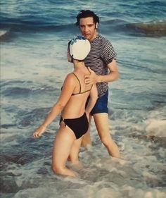 two people in the water at the beach, one is holding his arm around the other