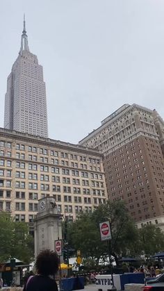 people walking in front of tall buildings on a cloudy day with the empire building in the background