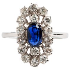 A large sapphire cluster ring, of 18k white gold. The oval cut Sapphire is set in a four claw setting surrounded by sixteen round cut diamonds totalling est. 1.12carat. A prominent and elegant piece, the ring size is P. The stones cover 2cm x 1cm and stands 6mm high. A unique piece within our carefully curated Vintage & Prestige fine jewellery collection, we are delighted to present the item above. Sapphire Cluster Ring, Double Strand Necklace, Claw Setting, Tanzanite Ring, Curated Vintage, Fine Jewelry Collection, Diamond Cluster Ring, Quartz Necklace, June Birth Stone