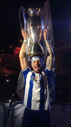 a man holding up a trophy on top of a soccer field