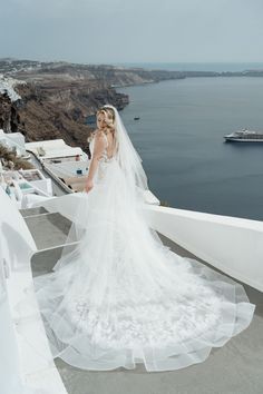 a bride and groom standing on the edge of a cliff looking out at the ocean