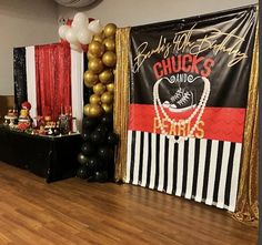 an event with black and gold balloons, white and red striped curtains, and a sign that says chuck's diners