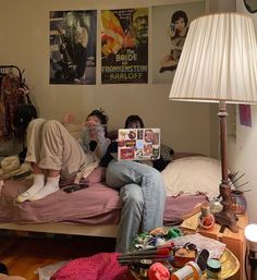 two people sitting on a bed with posters above them