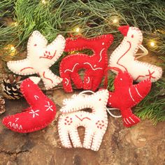 christmas ornaments are sitting on the ground next to pine cones and fir tree branches, which have been decorated with red and white felt