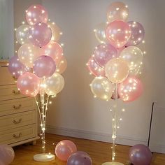 two tall vases filled with balloons on top of a wooden floor next to a mirror