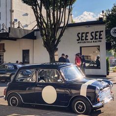 an old black and white car parked in front of a store