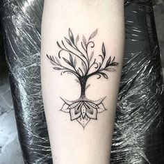 a black and white tree tattoo on the right arm, with leaves around it's branches