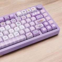 a purple computer keyboard sitting on top of a wooden table