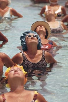 some people are in the water and one is wearing a sun hat with her eyes closed