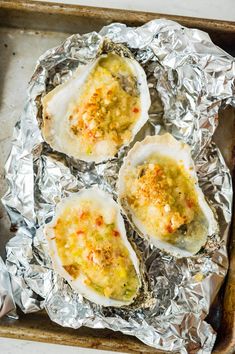 four cooked oysters on tin foil in a baking pan, ready to be eaten