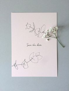 some white flowers are sitting on top of a card that says, save the date