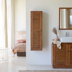 a bathroom with a sink, mirror and wooden shutters on the wall next to a bed