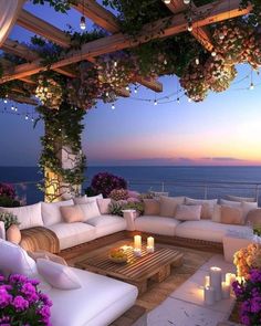 an outdoor living area with white furniture and flowers on the table, overlooking the ocean