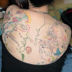 the back of a woman's shoulder with tattoos on it