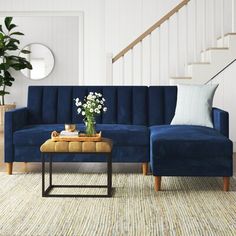 a living room with a blue couch and coffee table in front of the stair case